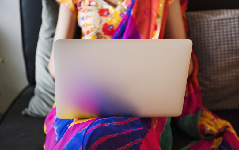 Woman in colorful sari reads a blog on her laptop.